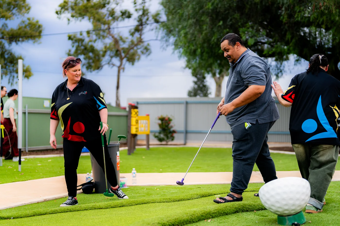 Participants and GIFSA support workers playing mini golf at the Activity Hub