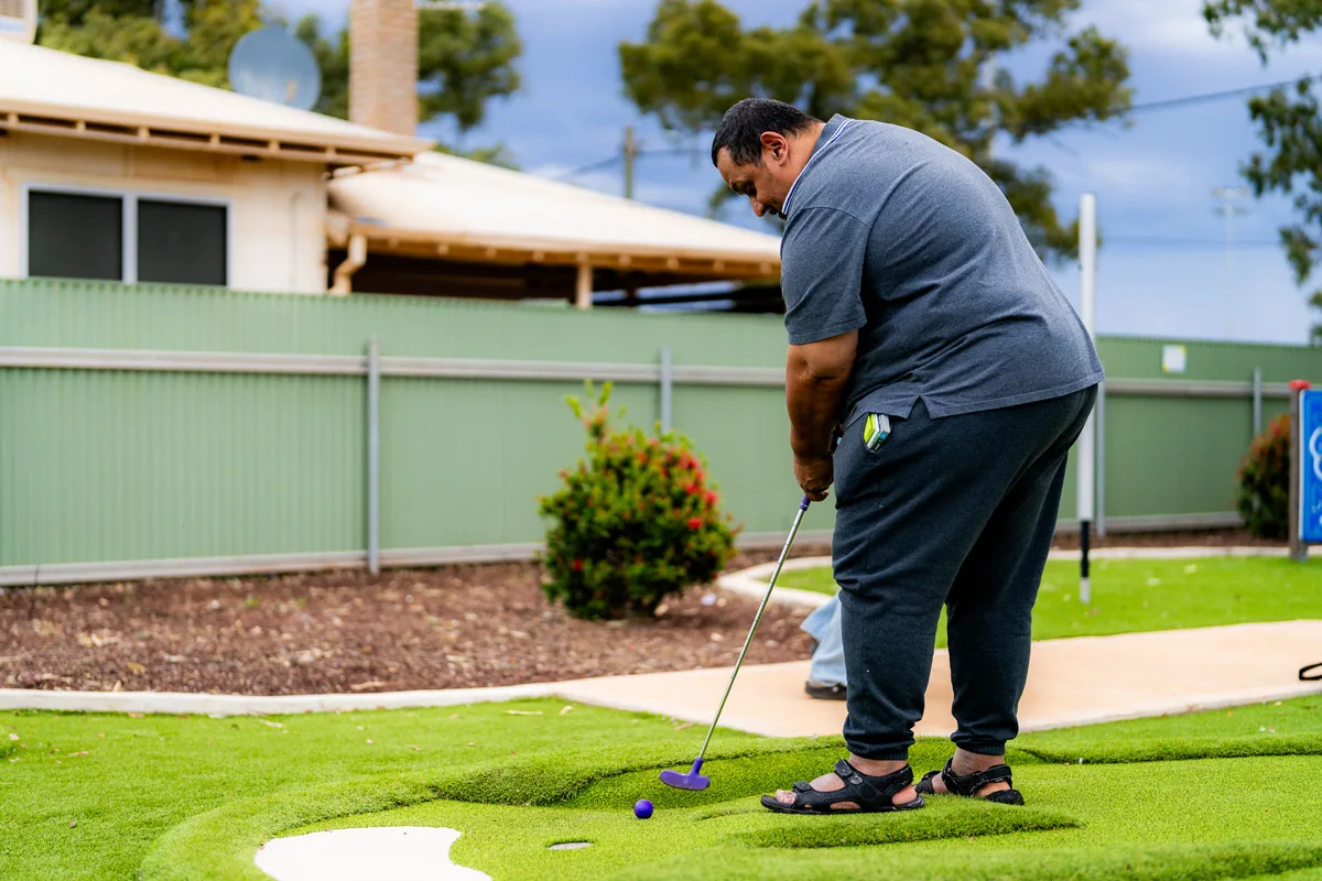 A participant lining up a putt on the mini golf course at the Activity Hub