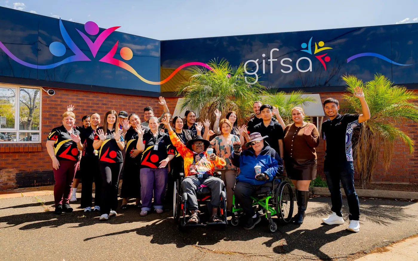 GIFSA staff and participants gathered outside the GIFSA office, waving and smiling