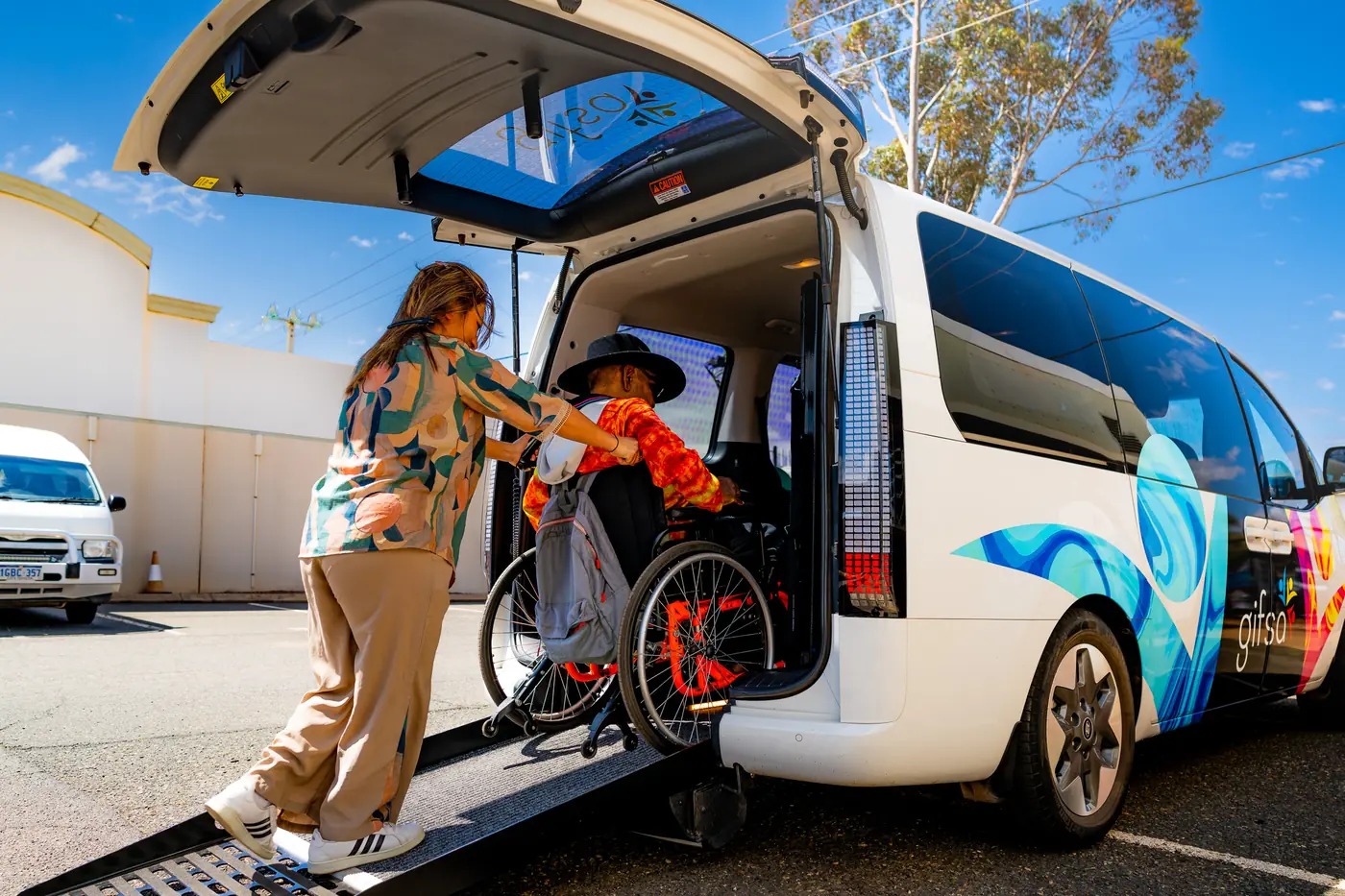 A support worker helping a participant in a wheelchair up the ramp into a GIFSA accessible van