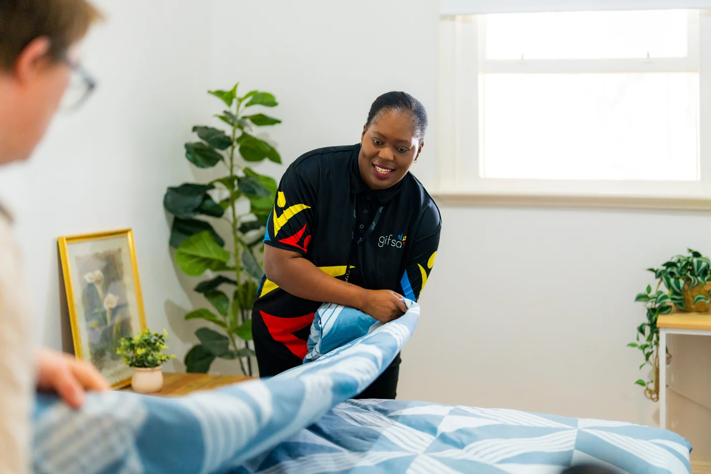 A GIFSA support worker helping a participant make a bed