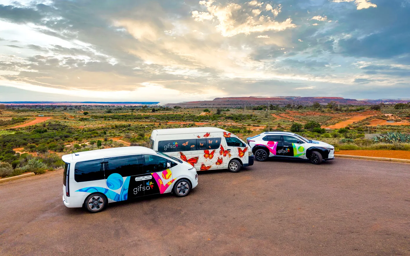 Three GIFSA vehicles parked on red dirt with the outback landscape behind