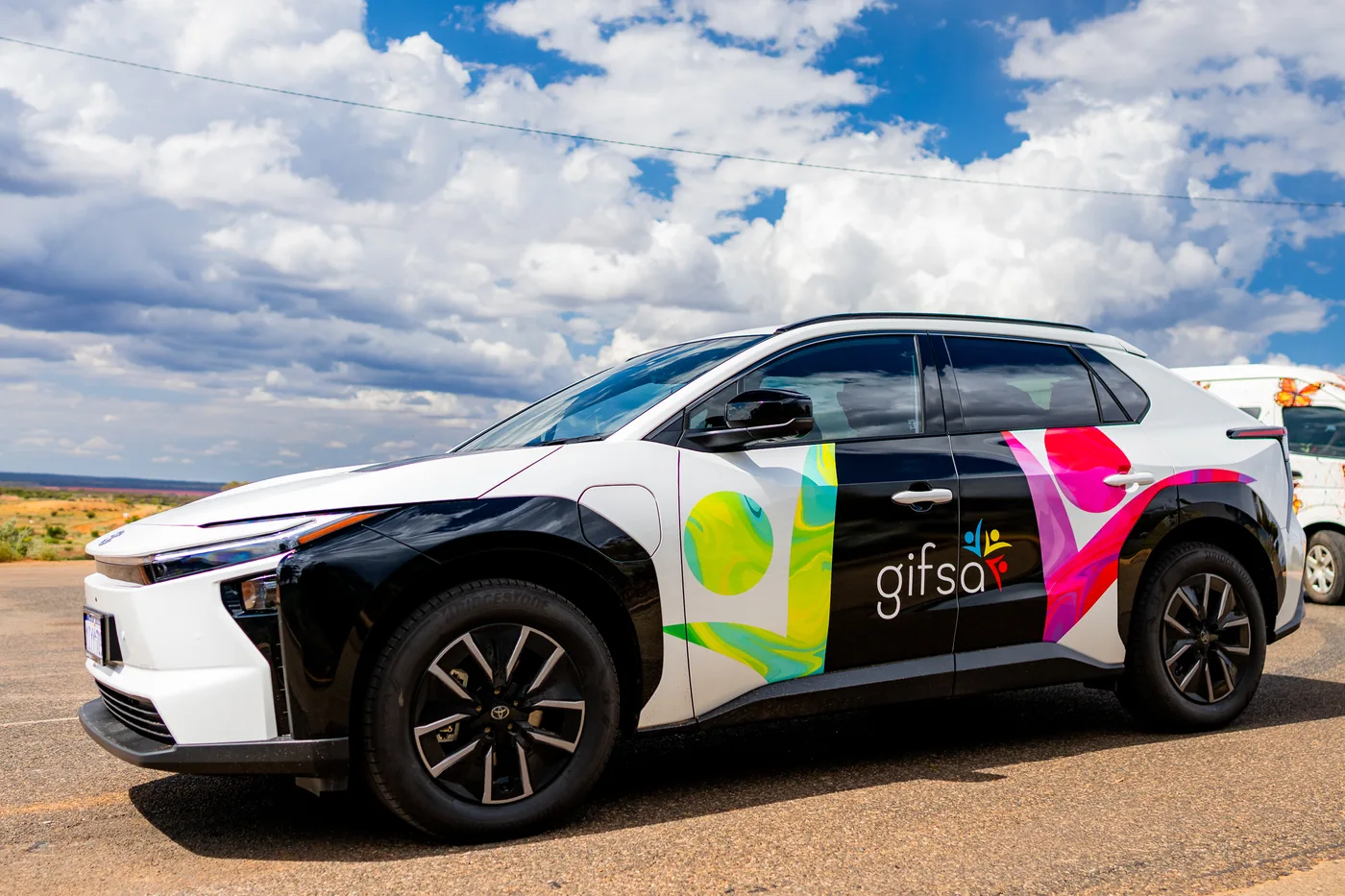 A GIFSA-branded electric car parked under a cloudy sky
