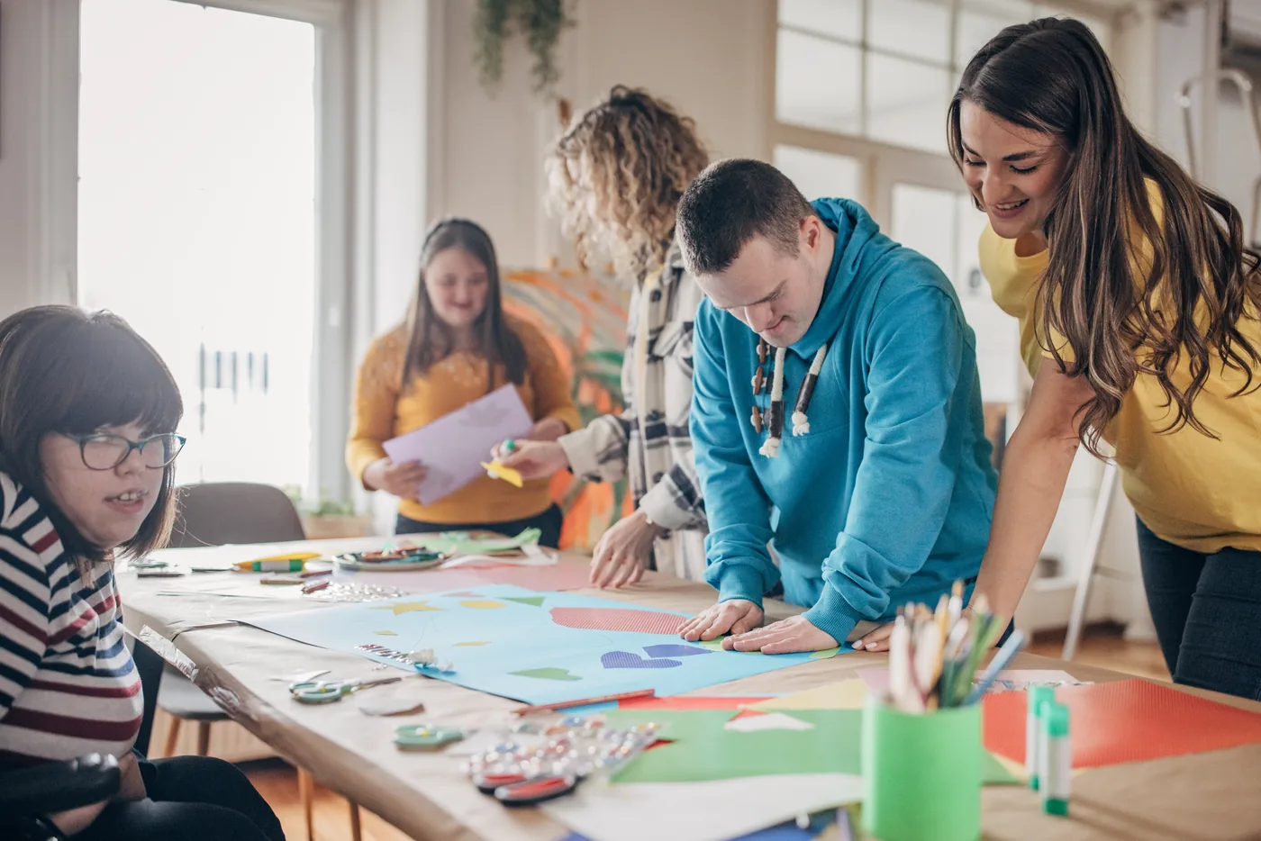 Adults with disability working on a group art project with support staff
